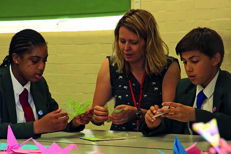 Two children and an adult woman make peace cranes.