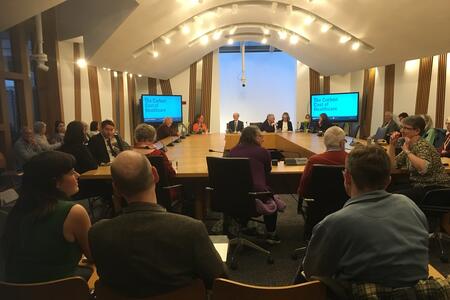 Picture of a room inside the Scottish Parliament with attendees facing a panel of speakers including Christine Grahame MSP and Maree Todd MSP