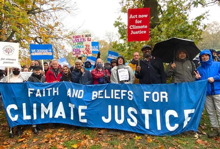 Pictures of various faith leaders standing in the rain holding a banner that says Faith and Beliefs for Climate Justice